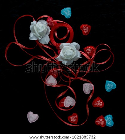 hearts I love you to the day of the holy valentine on a black background next to a white rose in blur and red ribbon