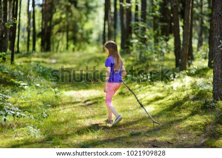 Cute little girl having fun during forest hike on beautiful summer day. Active family leisure with kids.