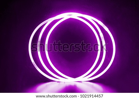 Three round bracelets of glow sticks of pink ultra violet with neon glow. With reflection on a black background