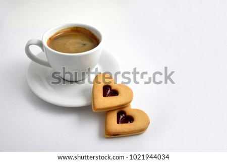 Cookie with coffee stock images. Cup of coffee on a white background. White cup of coffee with snack. Cup of coffee with cookie. Espresso with sweetness. Sweet biscuits hearts