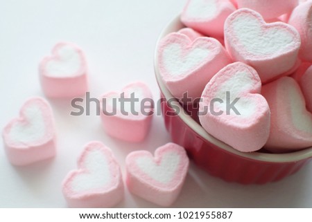 Marshmallows heart shape on red bowl and white background