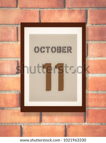 October 1st. 1 October calendar on the wood photo frame with brown brick background. Autumn day.