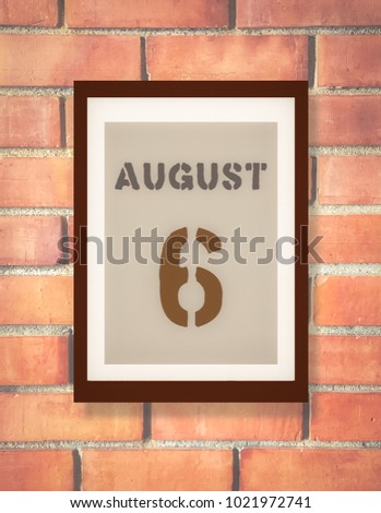 August 6th. 6 August calendar on the wood photo frame with brown brick background. Summer day