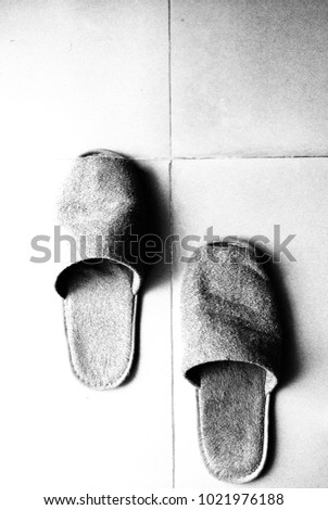 Vertical silhouette image style of fabric slippers place on ceramic tiles 