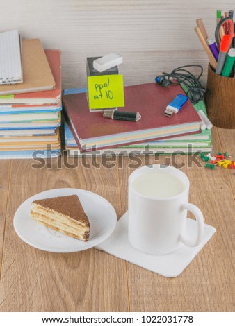 high school student: a mug of milk and a piece of cake on a plate, on the desktop, top view, vertical picture