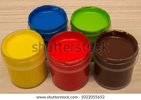 Finger paints in jars on a wooden background