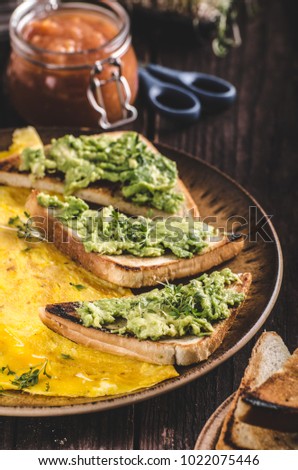 Egg omelette with garlic avocado toast, bio eggs and fresh herbs, homemade ketchup