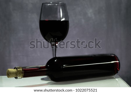 Glass of wine a bottle of red wine on a wooden table. Beautiful dark background