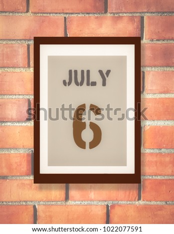 July 6. 6th July calendar on the wood photo frame with brown brick background. Summer day