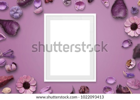 White picture frame on pink background surrounded with flower decorations.