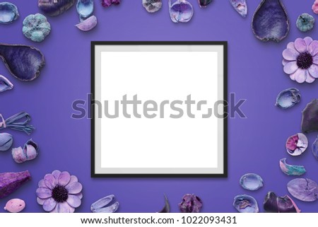 Picture frame on purple desk with flower decorations. Isolated frame for picture or text mockup. Top view.