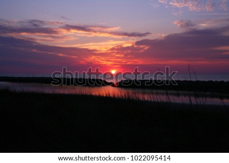 Natural Sunset in a lake, water front with Dark Ground. Countryside Landscape Under Colorful Sky At Sunset Dawn Sunrise. Over Skyline, tree silhouette and beautiful. Blurry focus,Summer season.