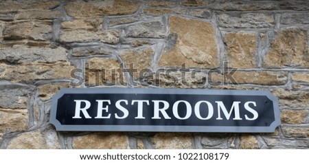 The restroom sign on the stone brick wall and on a close up view.