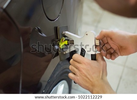 Body repair. The mechanic at the auto shop with tools to repair dents in car body. Royalty-Free Stock Photo #1022112229