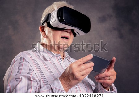 gray hairy elderly woman using virtual reality glasses and looking surprised