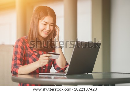 Asian woman using credit card shopping online in coffee shop vintage color tone.