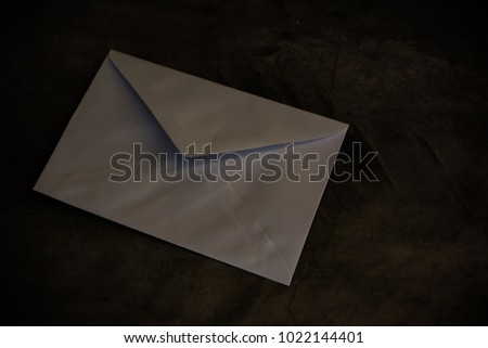 A white envelope on the dark floor. The isolated photo of blank envelope on a dark concrete floor.