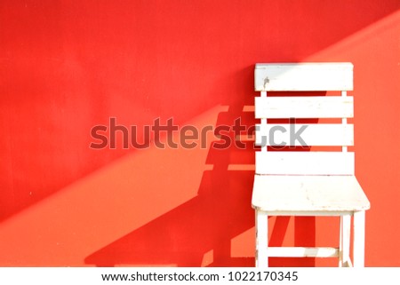 White wooden chair with red background right position.