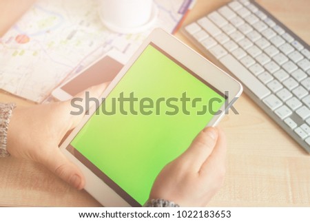 The man's hands with tablet with green chromakey. The white keyboard and the succulent plant on the wooden table background. Bangkok map and green screen.