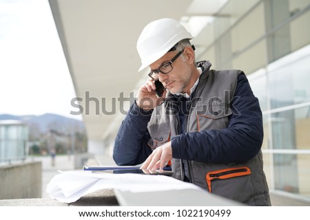 Engineer working on outdoor project and talking on phone  Royalty-Free Stock Photo #1022190499