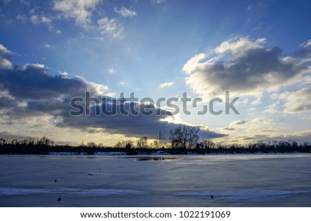 colorful winter sunset on frozen river ice with dramatic clouds