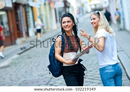 two attractive woman tourists looking at the map in the city