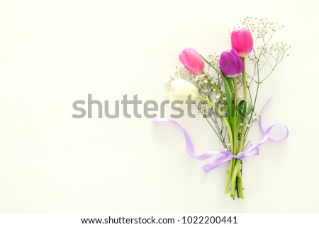 bouquet of pink and white tulips over pastel wooden background. Top view