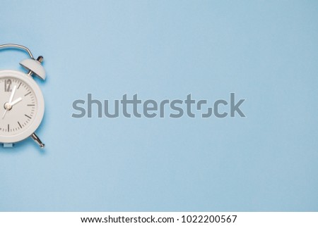 White clock on pastel blue background. Space for copy. Minimal concept.