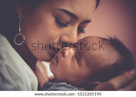 Portrait beautiful mother kiss her baby child. Mom nursing baby. mom and baby boy relax at home. Nursery interior. Mother breast feeding baby. Family at home. Mom's love. selected focus, vintage style
