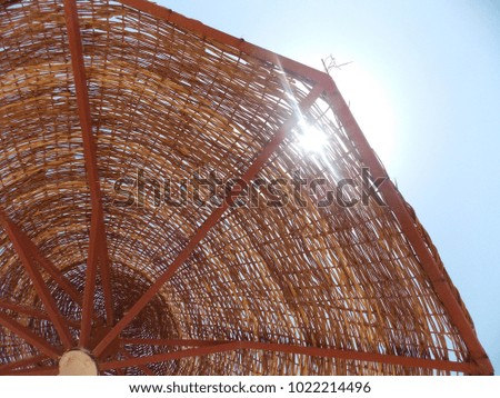 Abstract composition of cane parasol and blue sky, symbolically representing vacation on seaside.