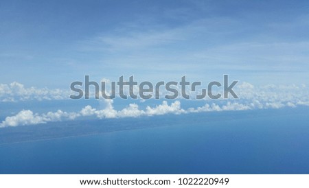 View through an airplane window with blue sea under.