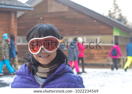 Asia kid girl in ski suit and goggle in winter season with snow background.