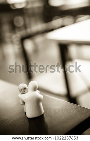 Ceramic couple dolls hugging on the wood table with blur table background. Love as the Defining Principle of ‘Family’ and past life love relationships concepts.