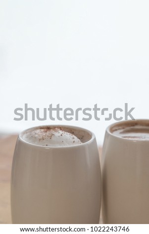 Two white cups of coffee stand on a world map against a light background