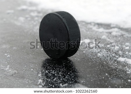 Black rubber hockey puck. With a place for text or images, isolated on snowy ice background. Fragment of ice hockey rink with. Concept hockey.