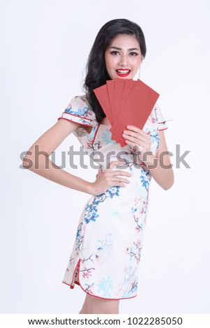Portrait of beautiful asian woman in red chinese dress traditional cheongsam. chinese new year concept. Beautiful smiling Chinese woman is holding red packet of Ang Pao present of Chinese New Year. 