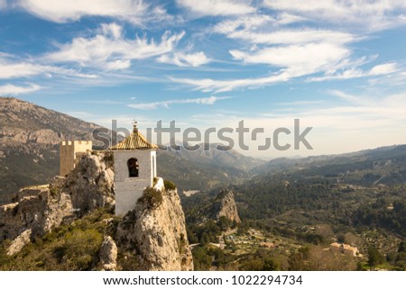 Guadelest/Spain - March 11, 2017: Sentinel tower at the crest of the fortified medieval city Guadelest with mountains in the background. 