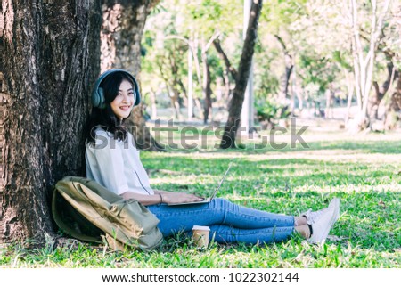 Woman relax and use a laptop computer sitting on grass in park