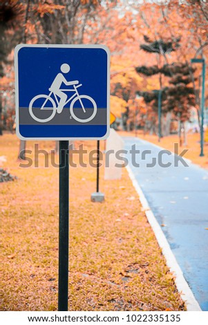 Blue traffic signs (warning signs) indicating biking directions for beware of bicycle embroidered along the blue bike trail inthe park. Health concept and selective focus.