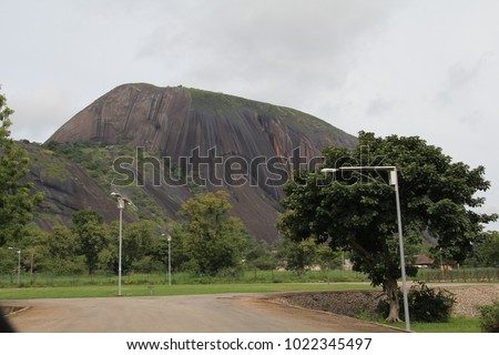 Zuma Rock, a large monolith, an igneous intrusion composed of gabbro and granodiorite, located in Niger State, Nigeria, near the capital Abuja. It's depicted on the 100 naira note. Royalty-Free Stock Photo #1022345497