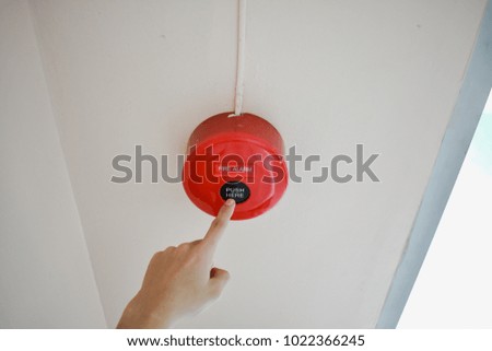 The hand of man is push fire alarm on the wall for safety.