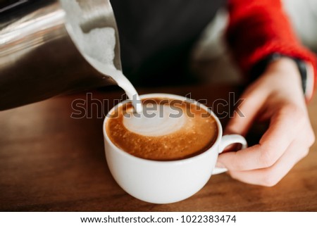 Barista is prepare making hot coffee cappuccino foam in white glass cup