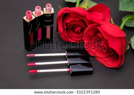Flowers rose,Powder and Liquid lipstick brush uses lips for women,Beauty cosmetic black background. Makeup essentials item isolated on black background