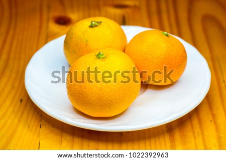 tangerines in white saucer on wooden table