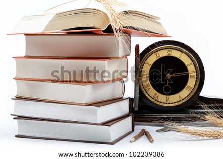 A stack of books and antique clock on a white background.