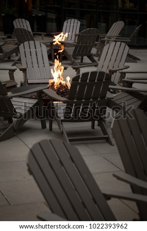 Fire pit surrounded by a circle of Adirondack chairs, with space for text in the dark foreground