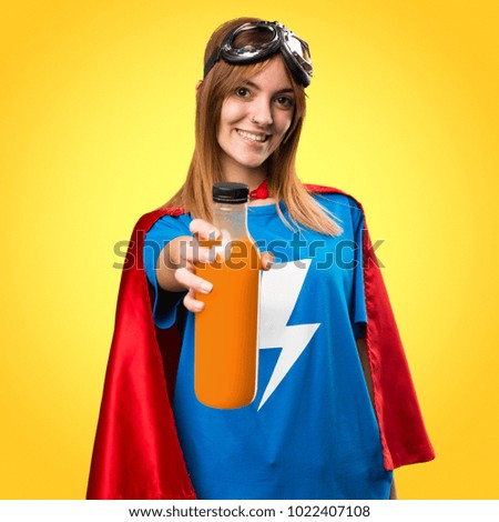 Pretty superhero girl holding a orange juice on colorful background
