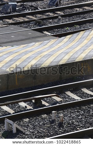 Graphic design composed of railway parallel lines and yellow stripes. Urban picture taken in a railway station in France. Close up view of the concrete quay photographied from above. Sunny day.  
