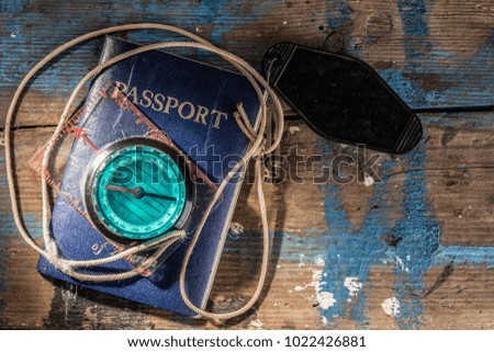 Passport, Hotel Room Key and Compass on a Paint Splatterd Wooden
