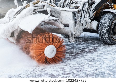 Cleaning snow concept. Tractor clears way after heavy snowfall. Worker ploughs white snow after snowstrom. Snow blowing machine in street